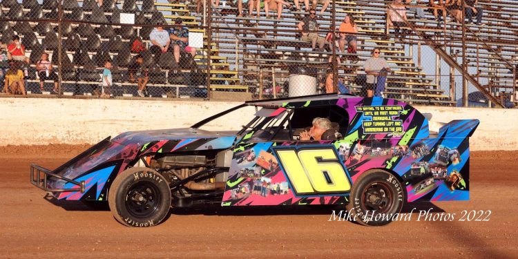 WAITING: Jim Bland sits in the seat of the No. 16 car as the fans rise in the background in anticipation of the national anthem before the start of the Rob Bland Memorial Race. Photo by Mike Howard Photography